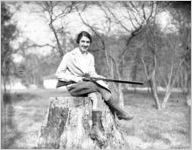 Woman with a shotgun sitting on a stump, Ichauway Plantation, Baker County, Georgia, 1931