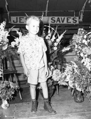 Child in front of a "Jesus Saves" sign at the Jessup Brothers Revival tent service, 1950