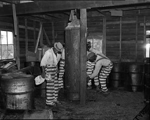 Afican American incarcerated individuals assisting in destruction of illicit whiskey still during Prohibition, 1930s