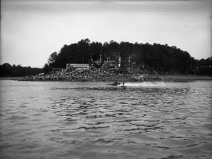 Crowd of people watching a boat race in Jackson Lake as boat speeds by, 1941