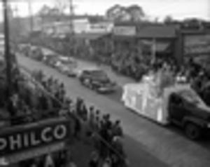 Crowd watching a Charlie Davidson parade travel through the main street of Lithonia, 1940s