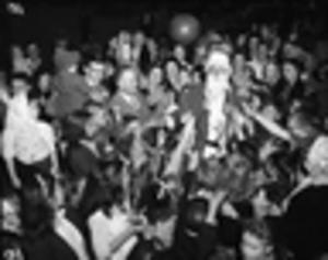 Children excitedly reaching for Santa during a Charlie Davidson holiday parade, 1940s
