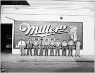 Staff of the Southern Detective Agency lined up outside their building in front of a large Miller Beer sign, Atlanta, Georgia, July 5, 1949