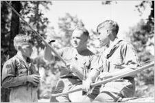 Boy Scouts with bow and arrows, leader is honing a bow, Georgia, July 1937.