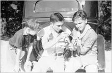 Young Boy Scouts feeding a baby Opossum with pipette, two chipmunks are crawling on boys' shirts, Georgia, July 1937