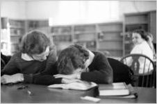 Agnes Scott College studens in College library; one has her head on the reading room table, Decatur, Georgia, March 1, 1937