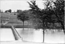 Large man-made pond with bridge going across it, Georgia, 1930s or 1940s