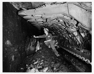 Miner inspecting Eickhoff EDW X 100L double-armed ranging drum shearer in mine in Benton, Illinois, circa 1970s