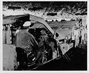 Continuous mining machine tearing coal from face of coal seam with steel teeth on rotating cutter head, 1974