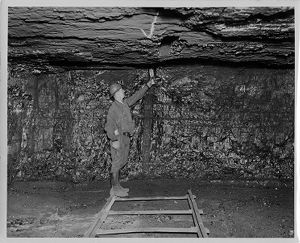 Miner using safety lamp to test for presence of methane gas in mine shaft, 1947