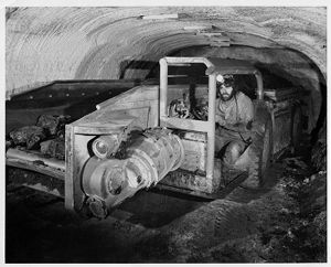 Shuttle car, a low-slung electric truck, rolls through a mine passageway, 1976