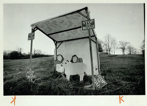 A nativity scene with "Stop the Road" signs posted around it, undated