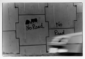 Part of parkway overpass support wall spray painted with "No Road"