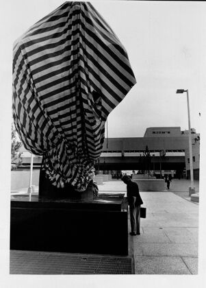 Man stops to read sign about "The Phoenix," a statue outside the North Broad Pedestrian Mall, undated