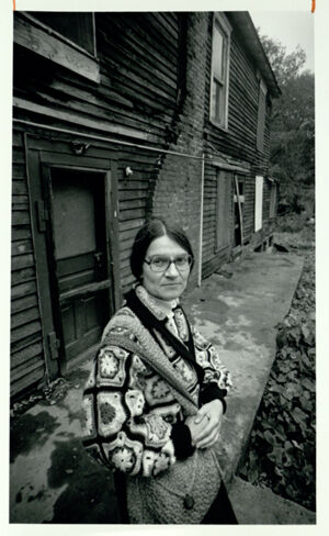 Virginia Wadsley stands on a porch that is to be restored, November 13, 1983
