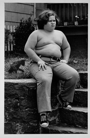 Boy outside a house with his kitten, July 1, 1976