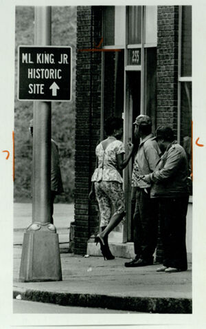 A woman entering a bar at Bell Street and Auburn Avenue where King Center signs are visible, October 16, 1983