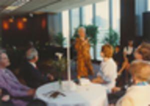 Woman singing, with man accompanying on piano in background