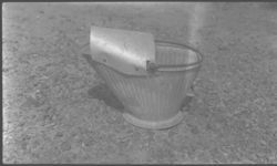 Coal scuttle with apron designed by Fred Haley for using coal. Apron prevents spilling of coal when pouring in stove