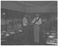 L.W. Eberhardt, assistant director, receiving shotgun from Harold Brown, Colquitt county agent. Other South Central Georgia county agents in background