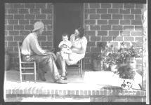 Howard Pope, operator, with his wife and baby on porch of new home