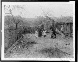 [Two African American women with two girls and a dog in backyard(?)]