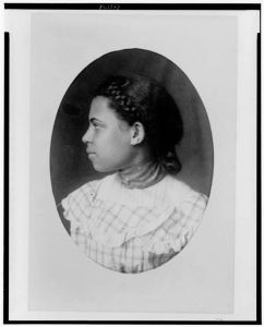 [African American girl with braided hair, head-and-shoulders portrait, facing left]