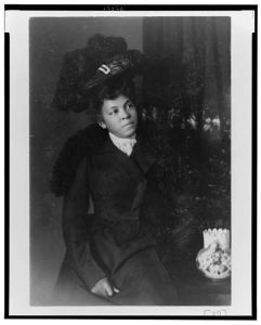 [African American woman, three-quarter length portrait, facing slightly right, wearing hat]