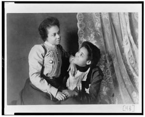 [Two African American women, three-quarter length portrait, seated, facing each other]