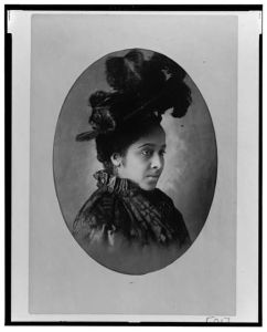 [African American woman, head-and-shoulders portrait, wearing hat, facing right]