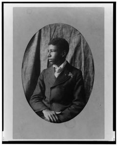 [Young African American man, half-length portrait, seated, facing left]
