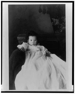 [African American infant, seated in chair, wearing christening gown, facing front]