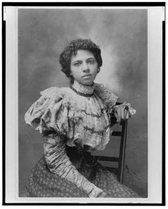 [African American woman, three-quarter length portrait, seated with left arm over back of chair, facing front]