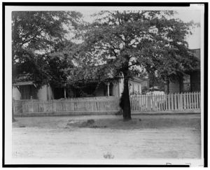 [Houses with picket fence on unpaved road in Georgia]