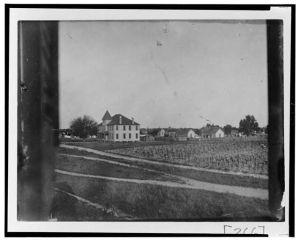 [Large building (residence or meeting house) with outbuildings and cultivated fields]
