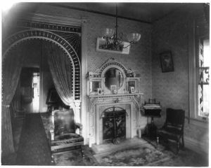 [Interior view of room showing chandelier, decorative arch, fireplace, and furniture]