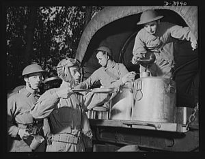 Fort Benning. Armored forces. Names like "Hell Buggy" and "Wildcat" are  painted on the helmets of these armored force trainees lined up for chow at Fort Benning, Georgia. As long as a soldier can eat and give disrespectful names to his equipment, he's going along alright