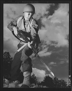 Fort Benning infantry. Slow down, Adolph. The road ahead is blocked. When this fine American soldier, just finishing a hardening up course at Fort Benning, Georgia, gives you the red light, remember he's an expert at stopping traffic