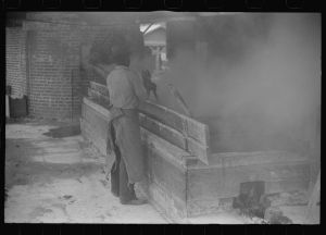 [Untitled photo, possibly related to: Filtering hot rosin through sieves at a turpentine works in Statesboro, Georgia]
