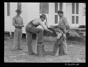 [Untitled photo, possibly related to: Farmers at Hazlehurst Farms Inc., sharpening an ax preparatory to going out to clear land. Hazlehurst, Georgia]