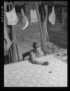 Woman who has not yet found a place to move out of the Hinesville Army camp area working on a quilt in her smokehouse. Near Hinesville, Georgia