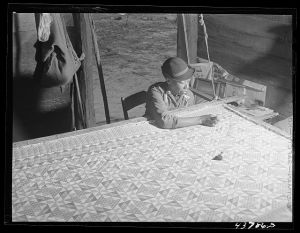 [Untitled photo, related to: A woman who has not yet found a place to move out of the Hinesville Army camp area working on a quilt in her smokehouse. Near Hinesville, Georgia]