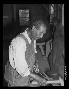 Negro farmer sharpening plow points at a new vocational school in Greene County, Georgia