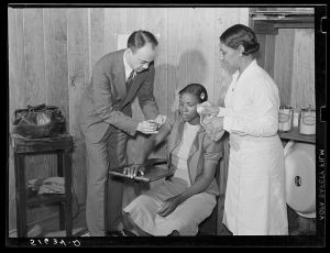 Dr. Thomas M. Adams, one of cooperative medical plan members, with project nurse Lillie May McCormick giving typhoid shot to Beatrice Loftly in health clinic. Flint River Farms, Georgia