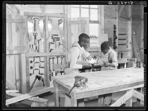 J.W. West and John Young sharpening crosscut saw in school shop class. Flint River Farms, Georgia