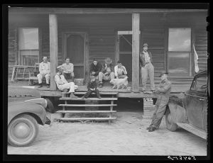 Construction workers on porch of local boarding house on highway near Fort Benning, Columbus, Georgia. They pay six dollars a week, several in a room. They are employed on Belair Construction job building defense housing project