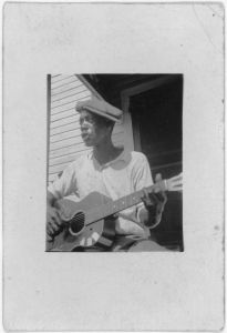 [Bill Tatnall, half-length portrait, seated, facing left, playing guitar, Frederica, Georgia]