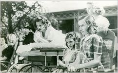 Photograph of patients gathered in front of Georgia Hall to view the hearse carrying Franklin Delano Roosevelt from the Little White House to the Warm Springs train station after his death, 1945