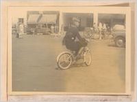 Photograph of a Shriner riding a small bicycle in a local parade, Sylvania, Georgia, 1951