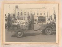 Photograph of two men riding in an animal cage as part of a humorous float in a local parade, Sylvania, Georgia, 1951